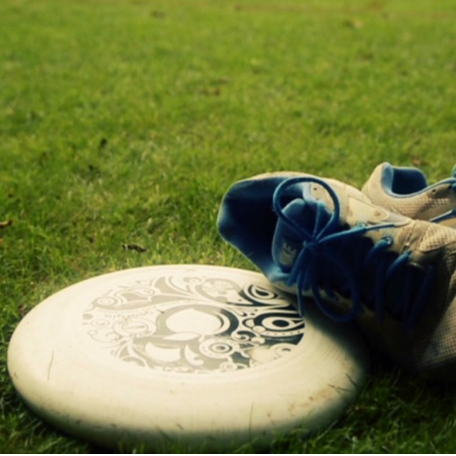White frisbee and blue athletic shoes on grass