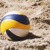 Yellow, blue, and white volleyball resting on sandy ground