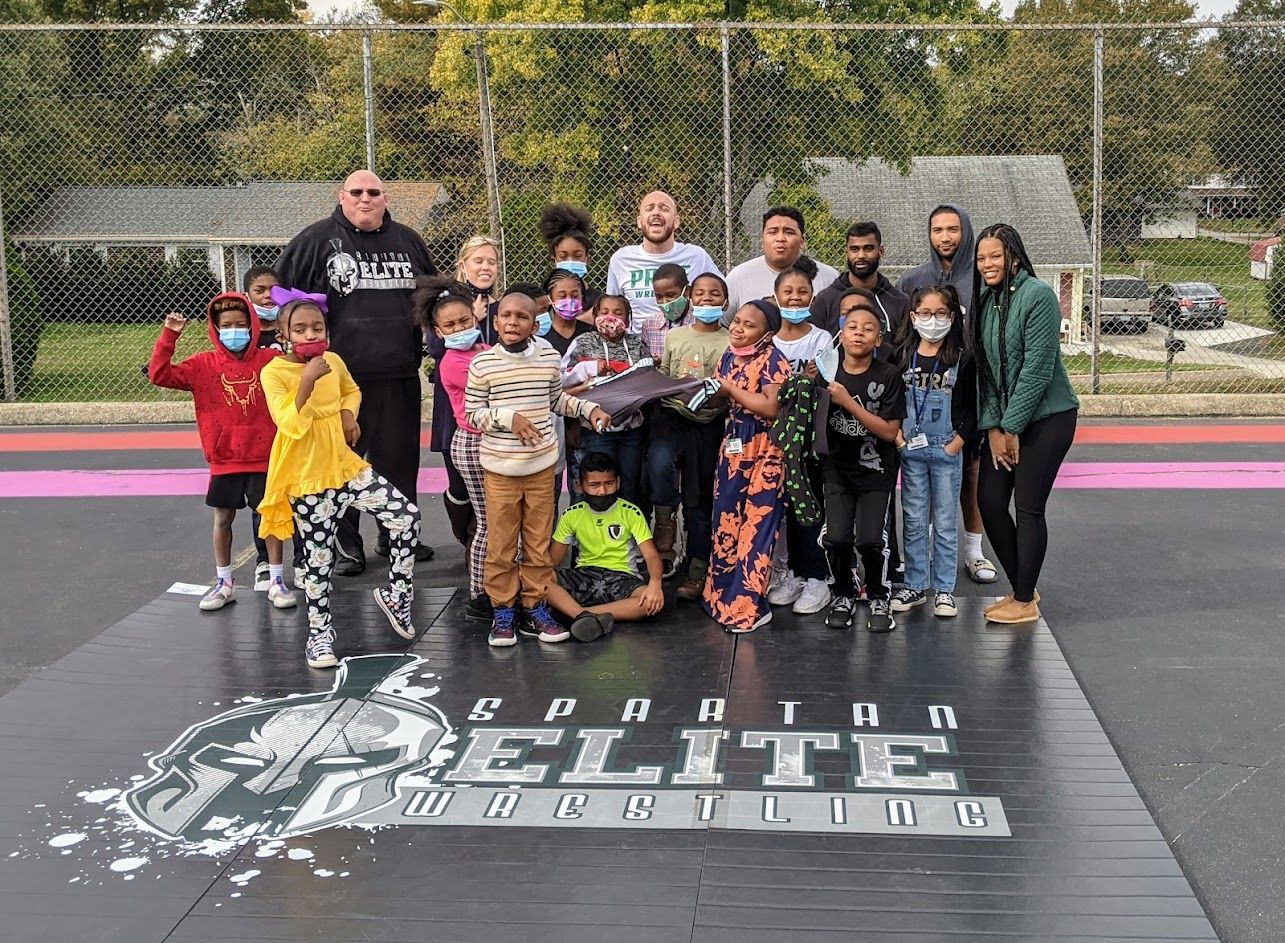 Group posing on a sports field in front of a large “Seattle Elite” banner at an outdoor event