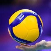 Yellow-and-blue volleyball hovering above a hand against a blurred purple background