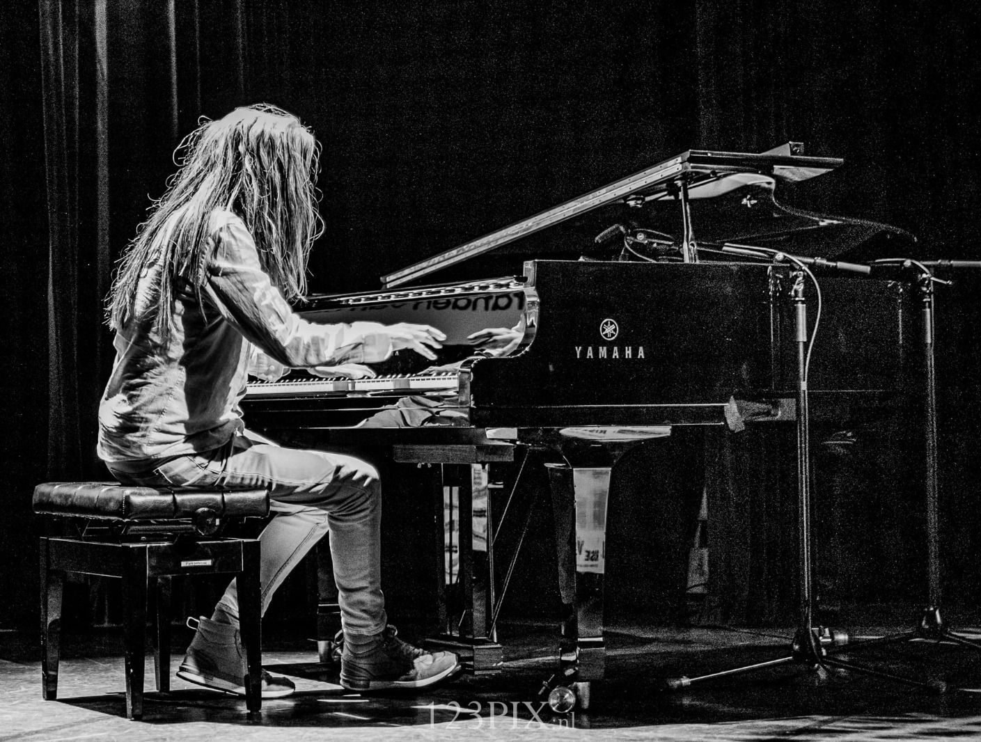 Een zwart-witfoto van een man die piano speelt