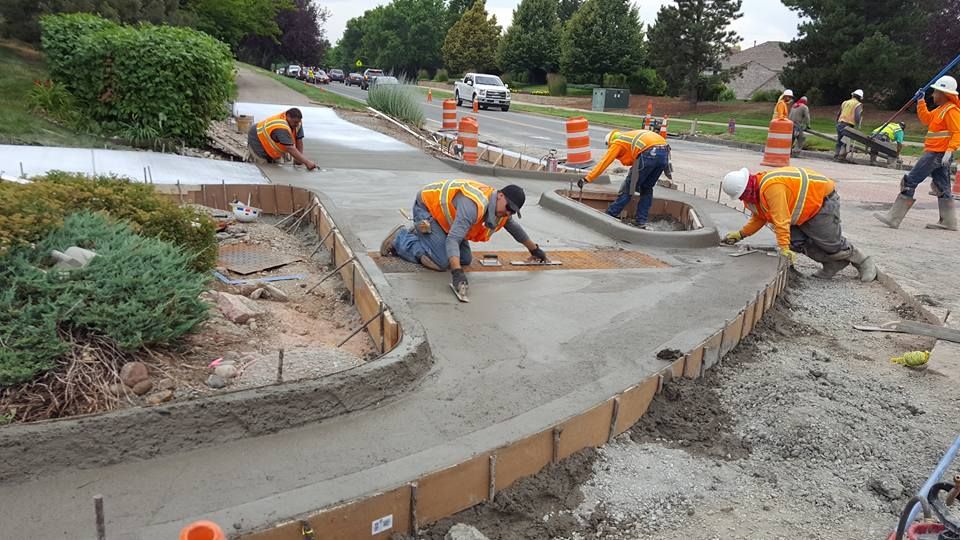 A group of construction workers are working on a sidewalk.