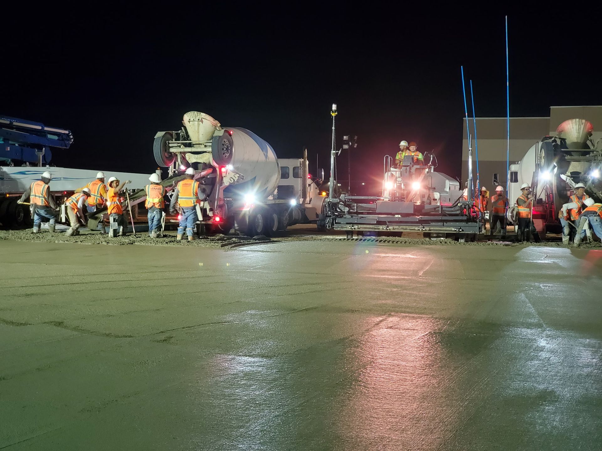 A group of construction workers are pouring concrete on a sidewalk.