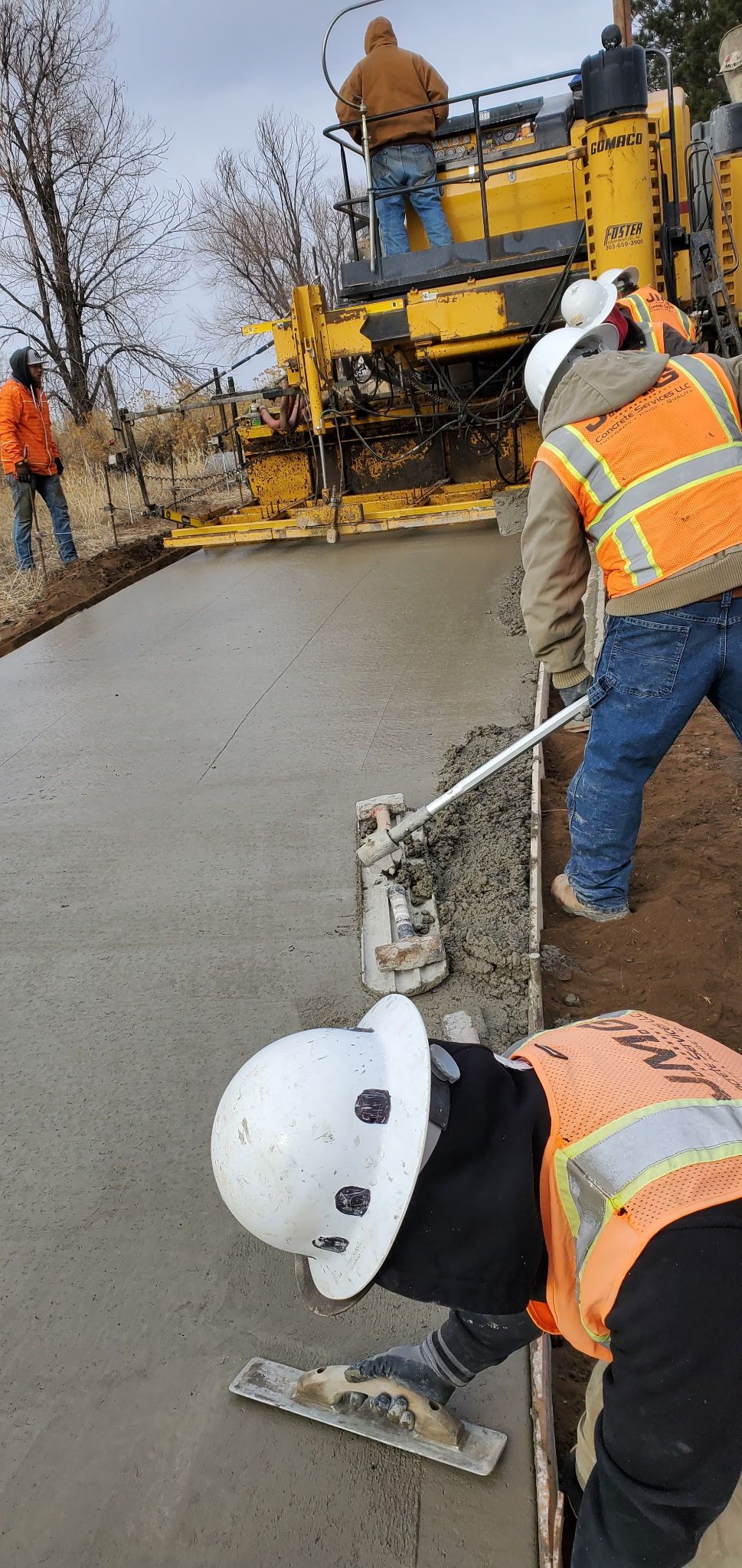 A group of construction workers are working on a concrete surface.
