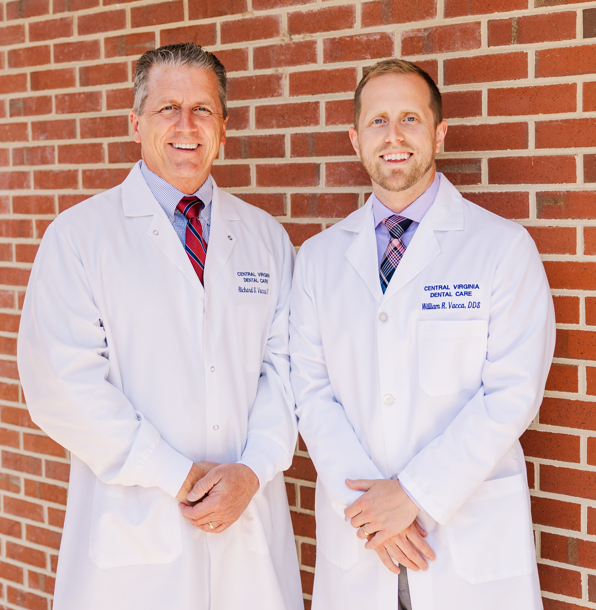 Two doctors in white lab coats standing in front of a brick wall