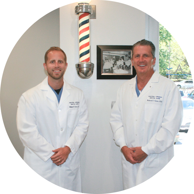 Two men in white lab coats standing in a barbershop with a striped pole centered between them.