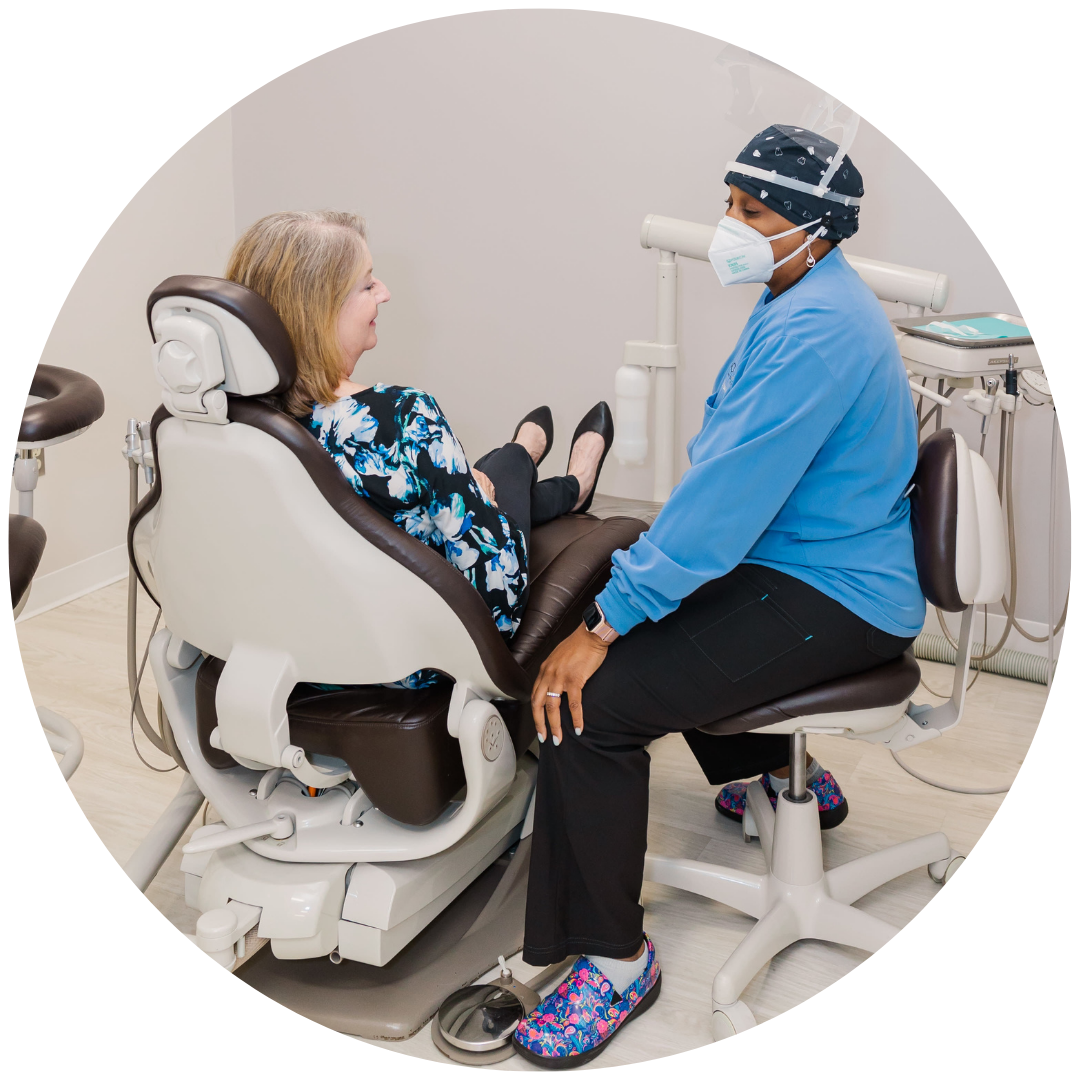 Dentist examines patient in a dental chair, both wearing masks, in a clinical office.
