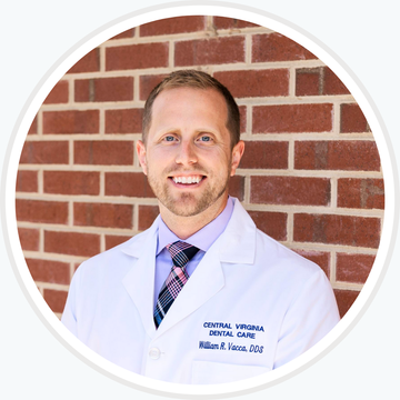 Smiling doctor in a white coat and tie standing in front of a brick wall