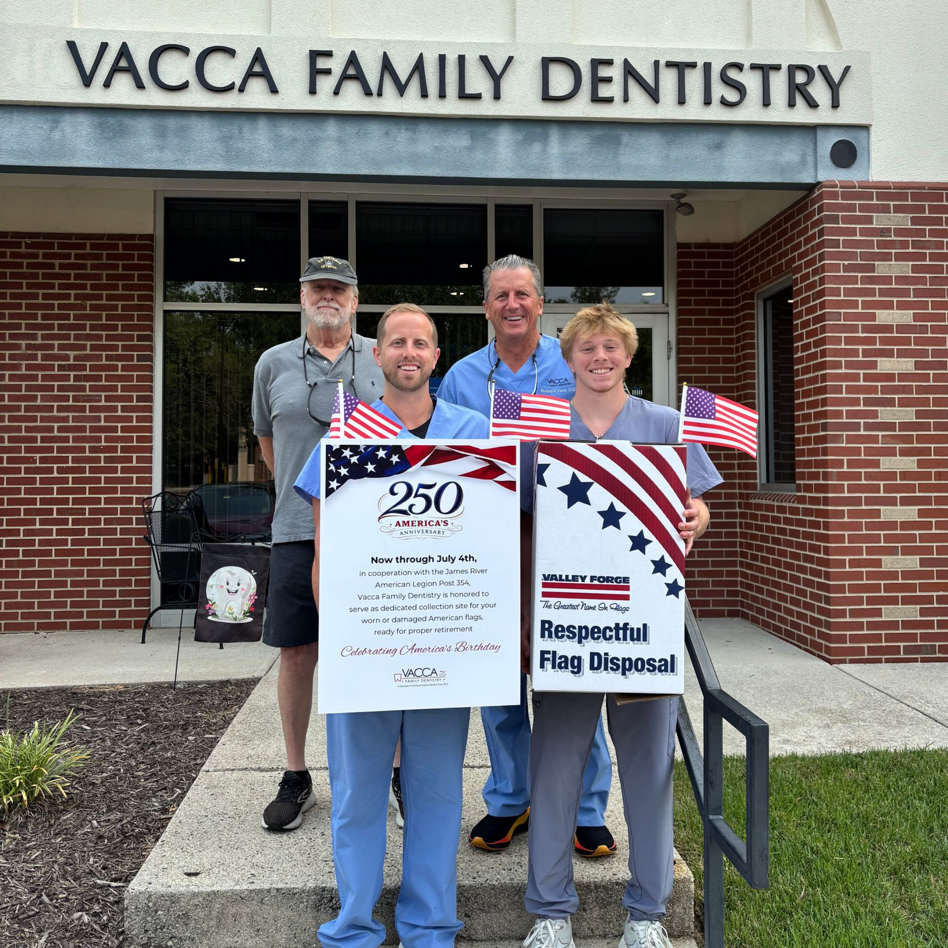 Four people holding a 250th anniversary sign and a “Respectful Flag Disposal” box outside Vacca Family Dentistry