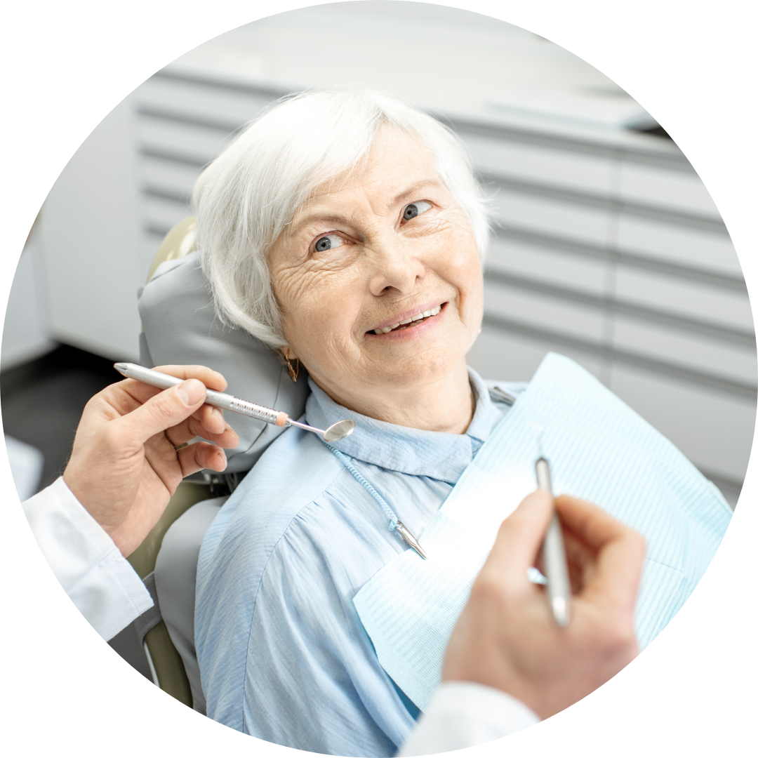 Dentist examining a smiling patient in a dental chair with tools and blue bib