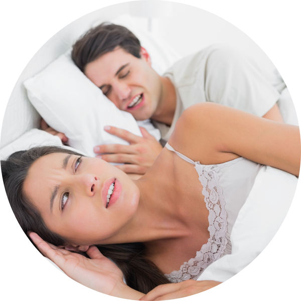 Couple in bed with one person awake and concerned while the other sleeps peacefully