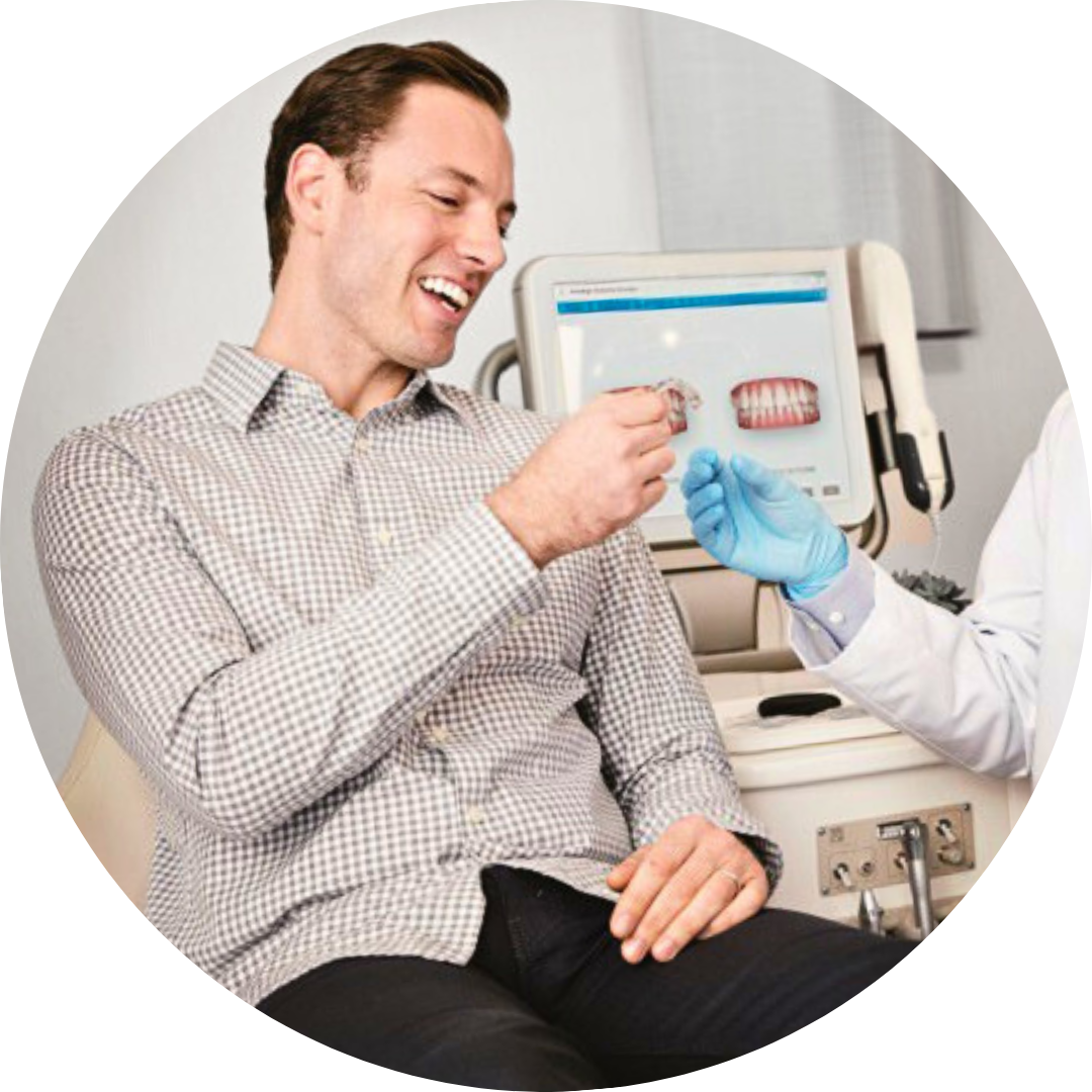 Patient smiling as a gloved clinician hands him a cup in a dental exam room