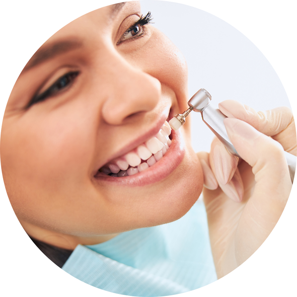 Dentist using a dental drill on a smiling patient’s teeth during a checkup