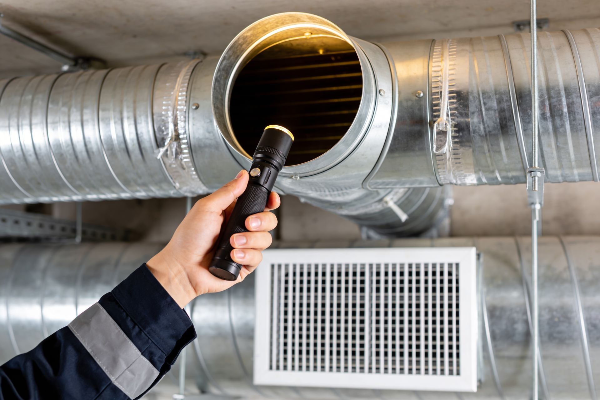 Outdoor air conditioner unit beside a house wall, with a fan grill and beige casing.