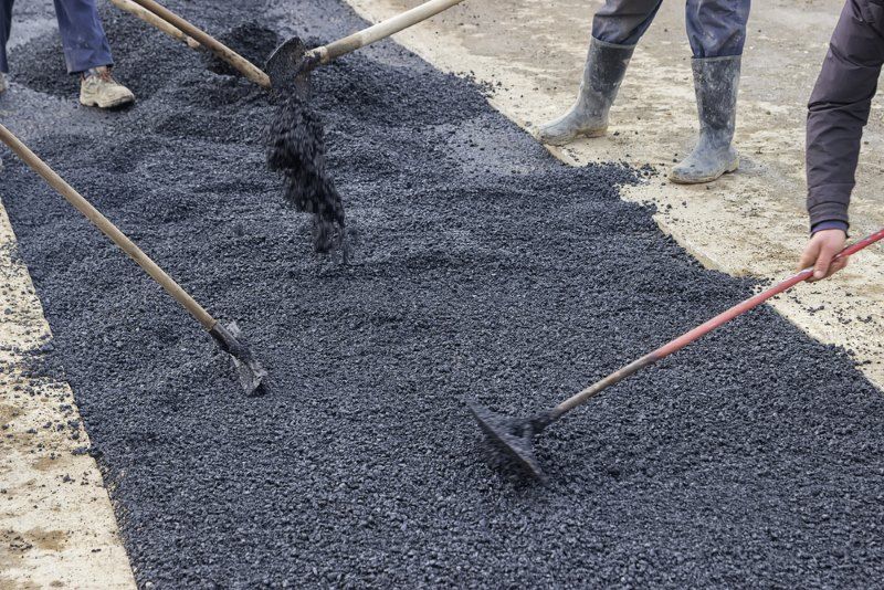 Workers Spread Asphalt On A Road With Rakes — Hunter Valley Bitumen In Dungog, NSW