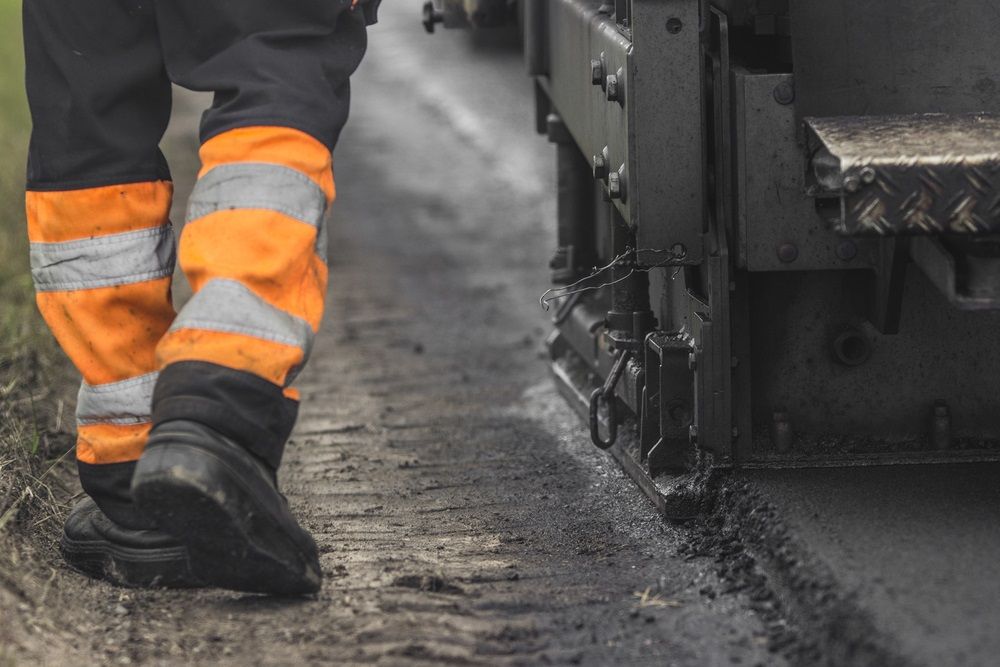 A Construction Worker In High-visibility Orange Pants — Hunter Valley Bitumen In Beresfield, NSW