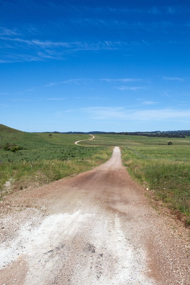 A Dirt Road Going Through a Grassy Field on A Sunny Day — Hunter Valley Bitumen In Hunter Valley, NSW