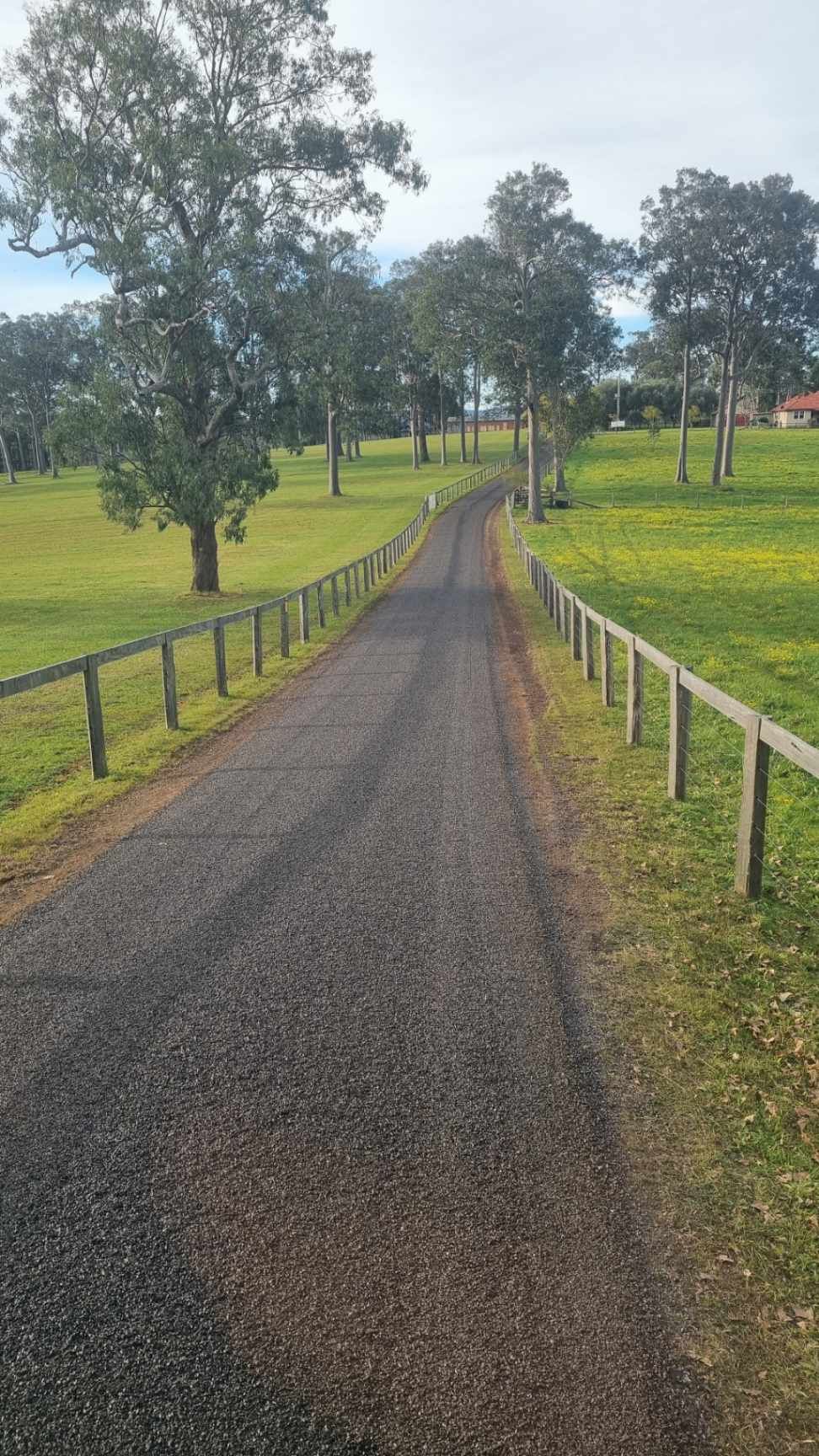 Freshly sealed driveway through green farmland with timber fencing – Hunter Valley Bitumen in Gresford, NSW