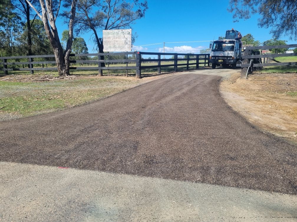 Newly sealed driveway curve leading to farm gate and truck.— Hunter Valley Bitumen In Gresford, NSW