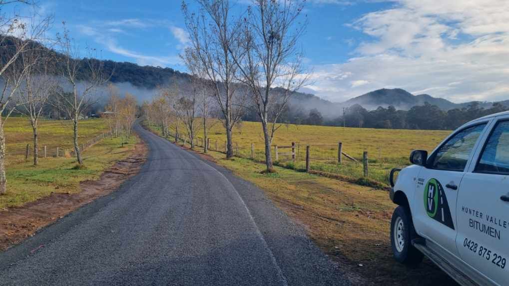 A gravel road through a rural landscape with fog in the distance, a white truck on the right.