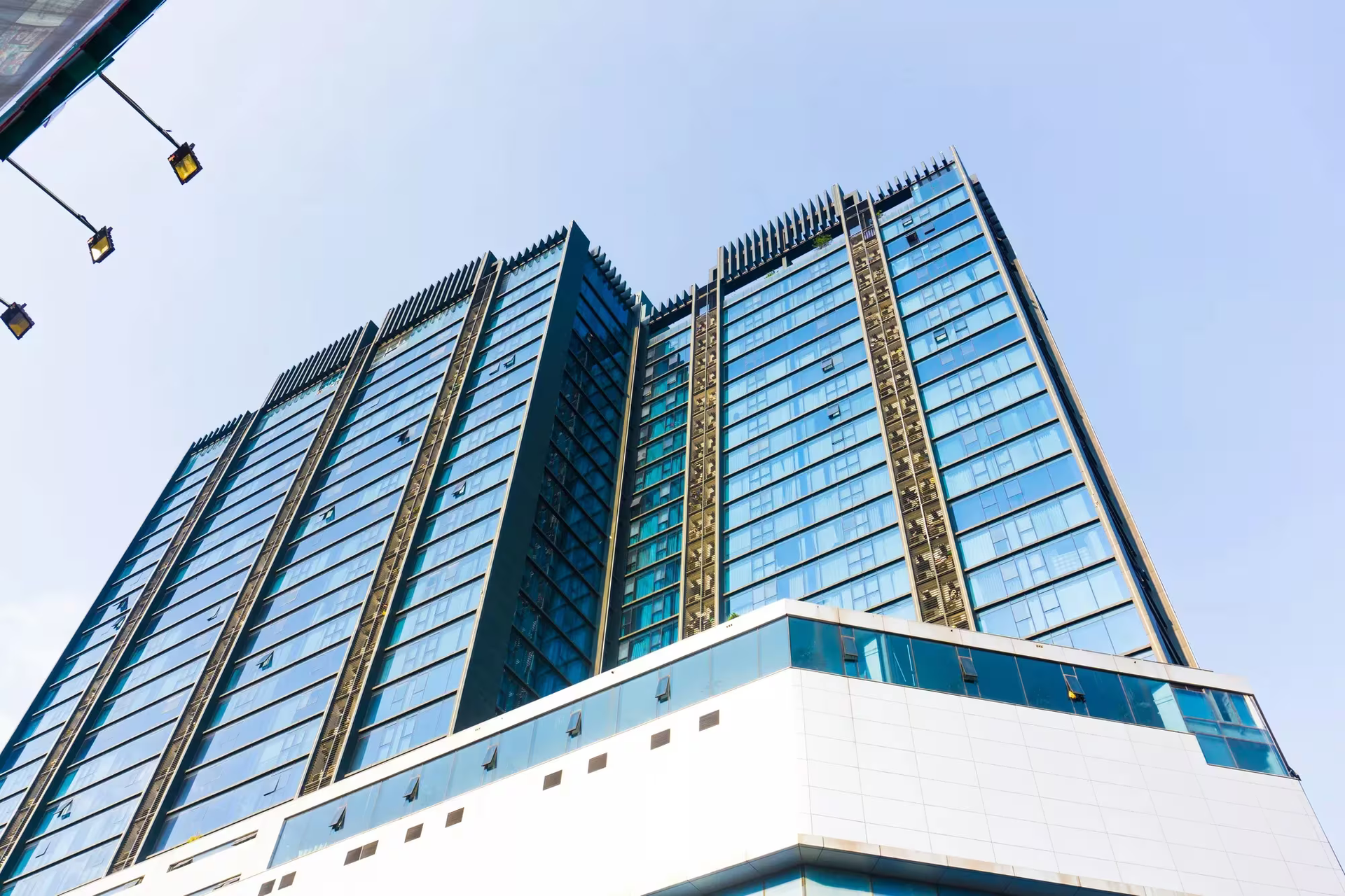 Modern glass office tower viewed from below against a blue sky