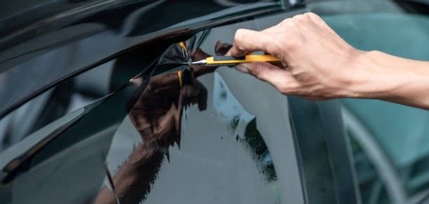 Hand applying a squeegee to a car window tint film