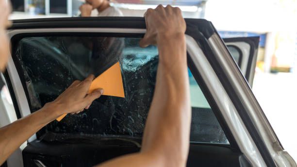 Person using a squeegee to clean a car window from inside the vehicle