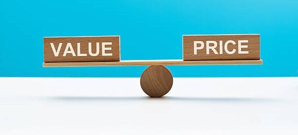 Wooden blocks labeled VALUE and PRICE balanced on a seesaw against a blue background