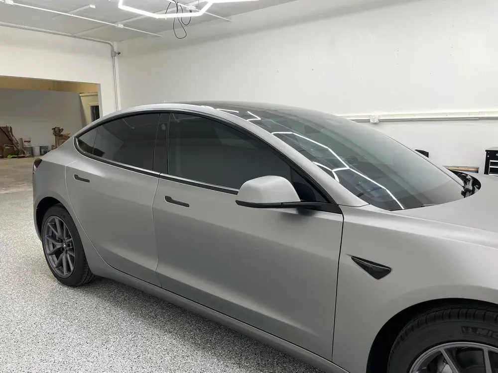 Silver Tesla sedan parked in a bright garage, side view.