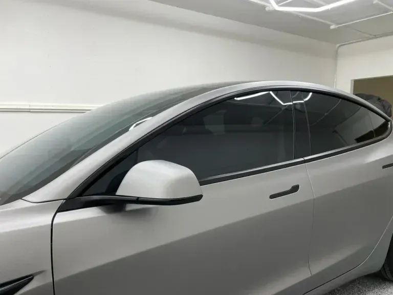 Silver car parked in a garage, side view with tinted windows