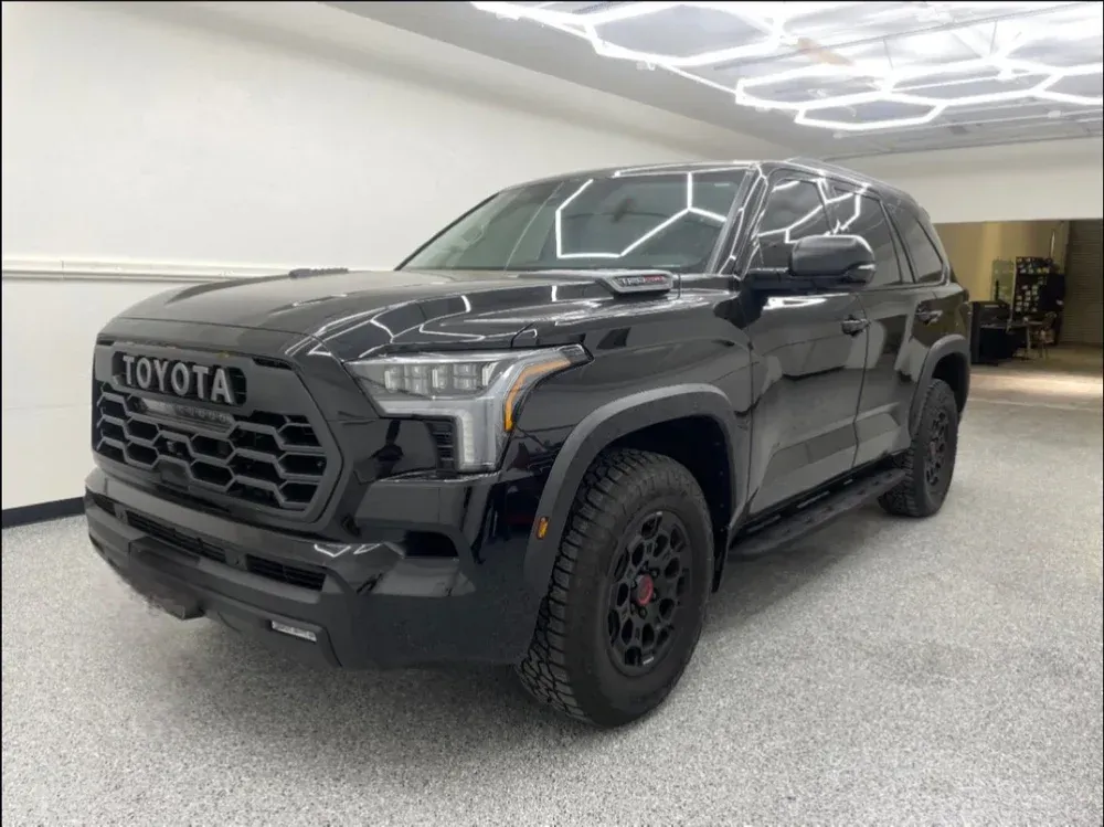 Black Toyota pickup truck parked indoors under bright ceiling lights