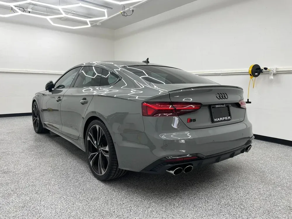 Gray Audi sedan parked in a bright garage, rear three-quarter view.