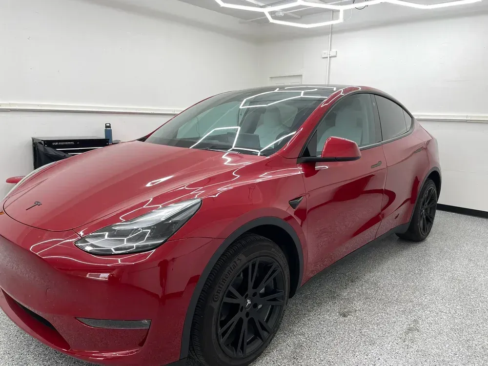 Red Tesla Model Y in a garage with gray walls and floor