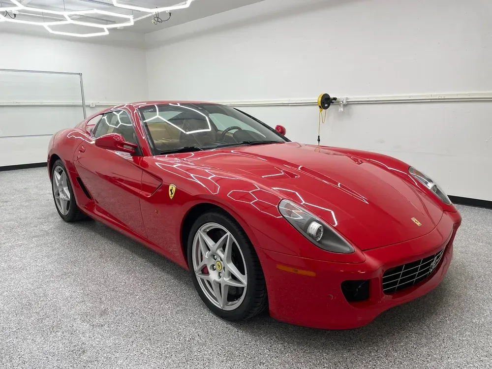 Red Ferrari sports car parked in a bright showroom, front-left view