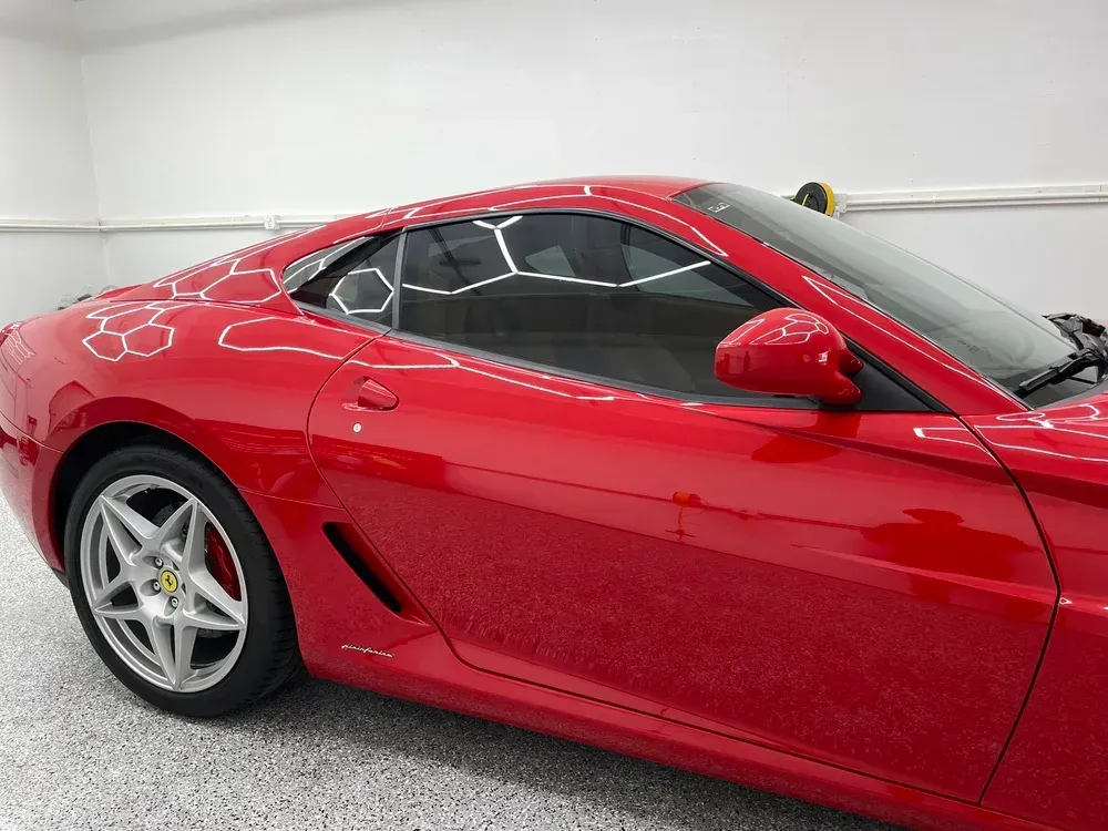 Red sports car in glossy finish parked indoors, side view.