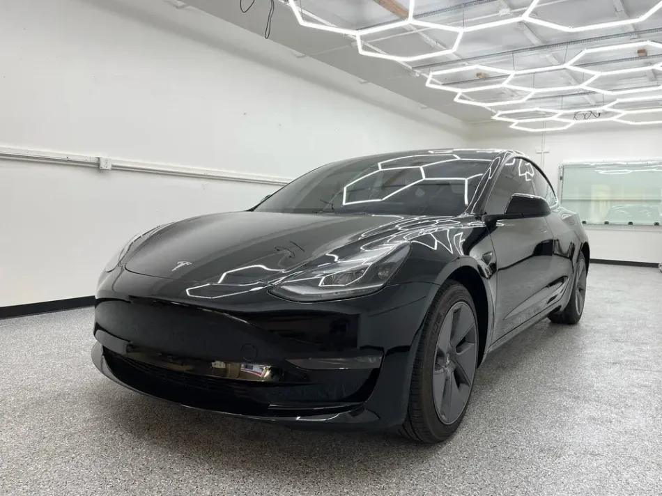 Black electric sedan parked indoors under bright geometric ceiling lights