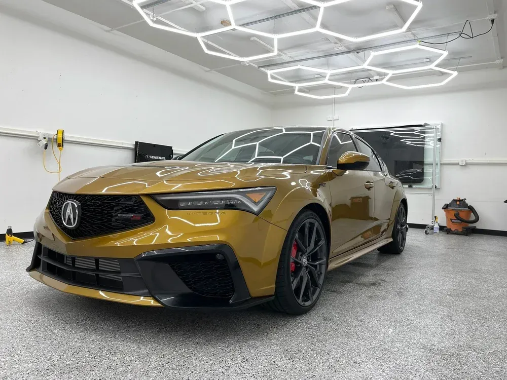 Gold Acura sedan parked in a bright garage with geometric ceiling lights