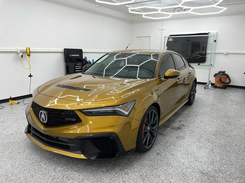 Gold Acura sedan parked in a bright garage with a speckled gray floor