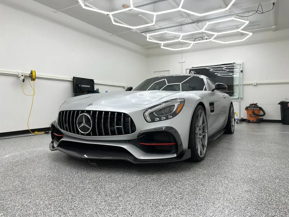 Silver Mercedes-AMG GT in a white garage under hexagonal ceiling lights