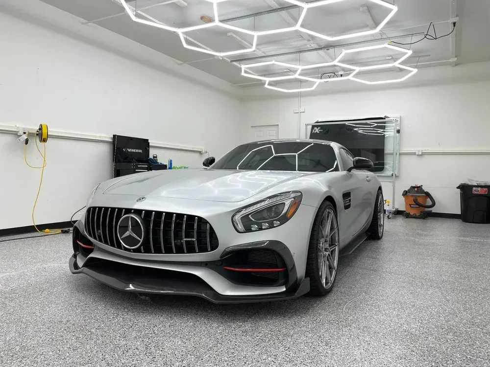 Silver Mercedes-AMG sports car in a clean garage with hexagonal ceiling lights