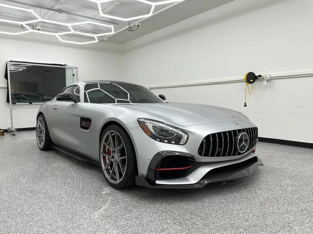 Silver Mercedes-AMG coupe parked in a bright garage with hexagonal ceiling lights