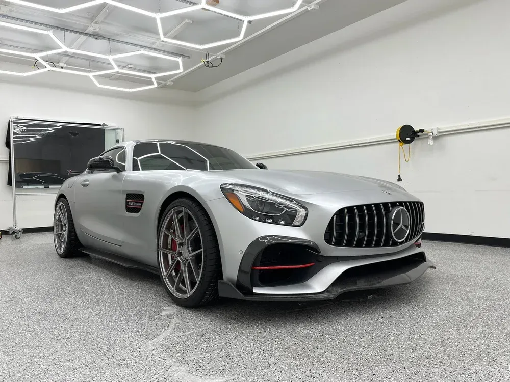 Silver Mercedes sports car parked in a bright modern garage with hexagon ceiling lights