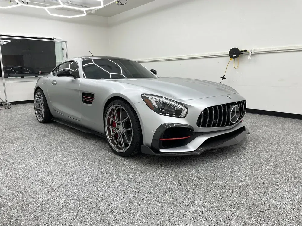 Silver sports car parked in a bright garage, viewed from the front-left side.