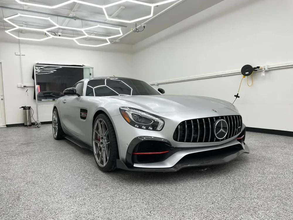 Silver Mercedes sports car parked in a bright garage with geometric ceiling lights