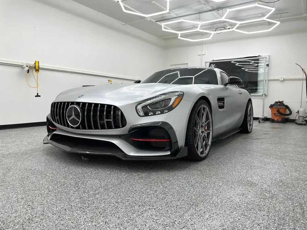 Silver Mercedes AMG coupe in a modern garage with hexagon ceiling lights