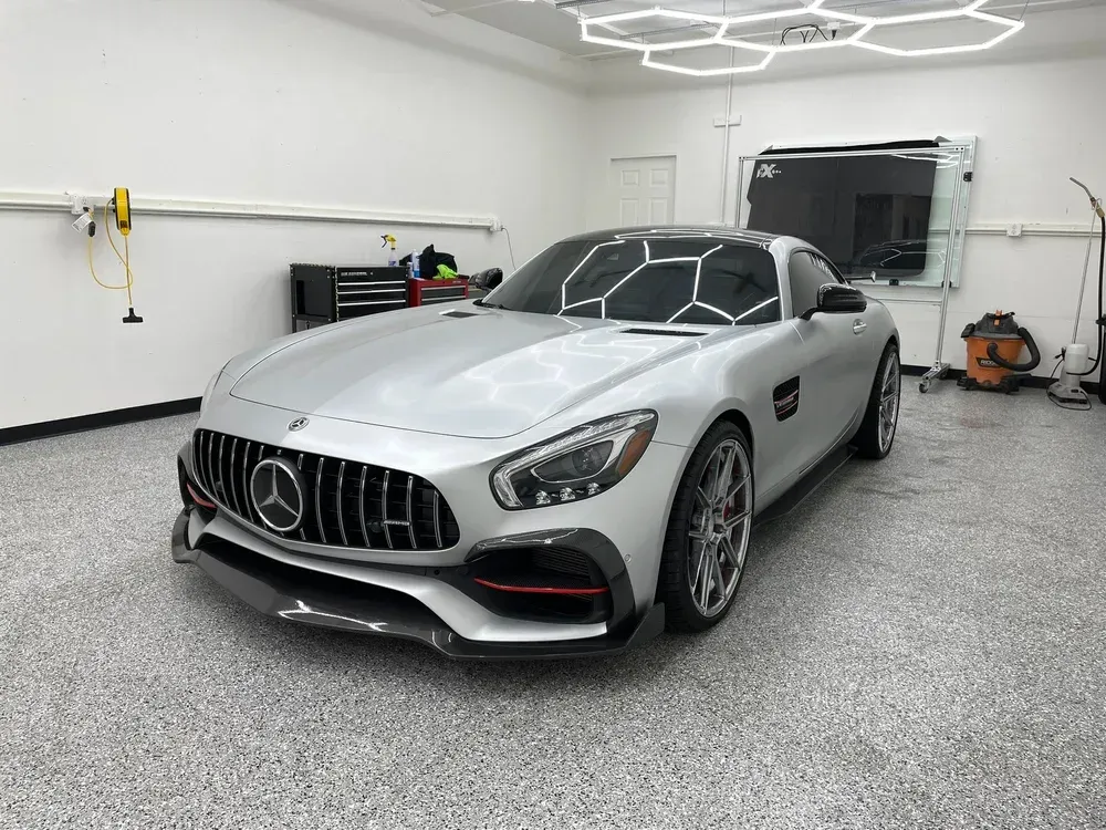 Silver Mercedes-AMG sports car in a clean garage with white walls and overhead lights