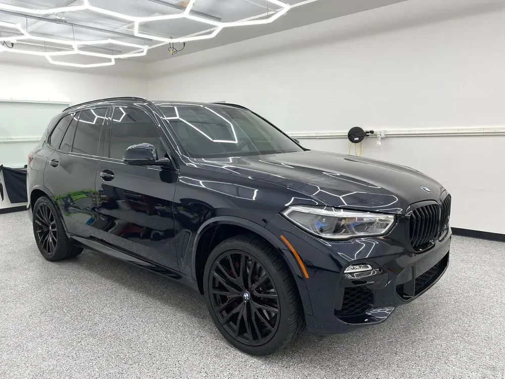 Black BMW SUV in a bright showroom with geometric ceiling lights
