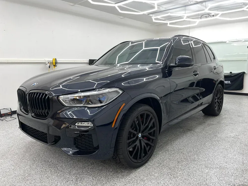 Black BMW SUV in a garage, front three-quarter view.