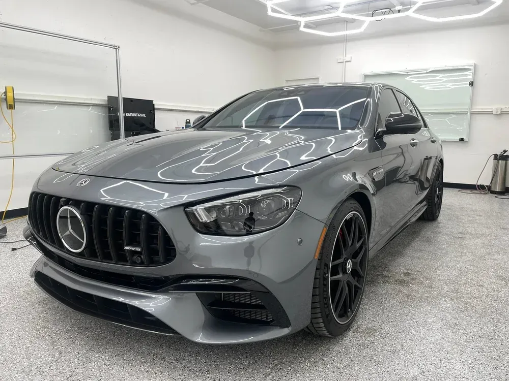 Gray Mercedes coupe in a garage with bright overhead lights and black rims