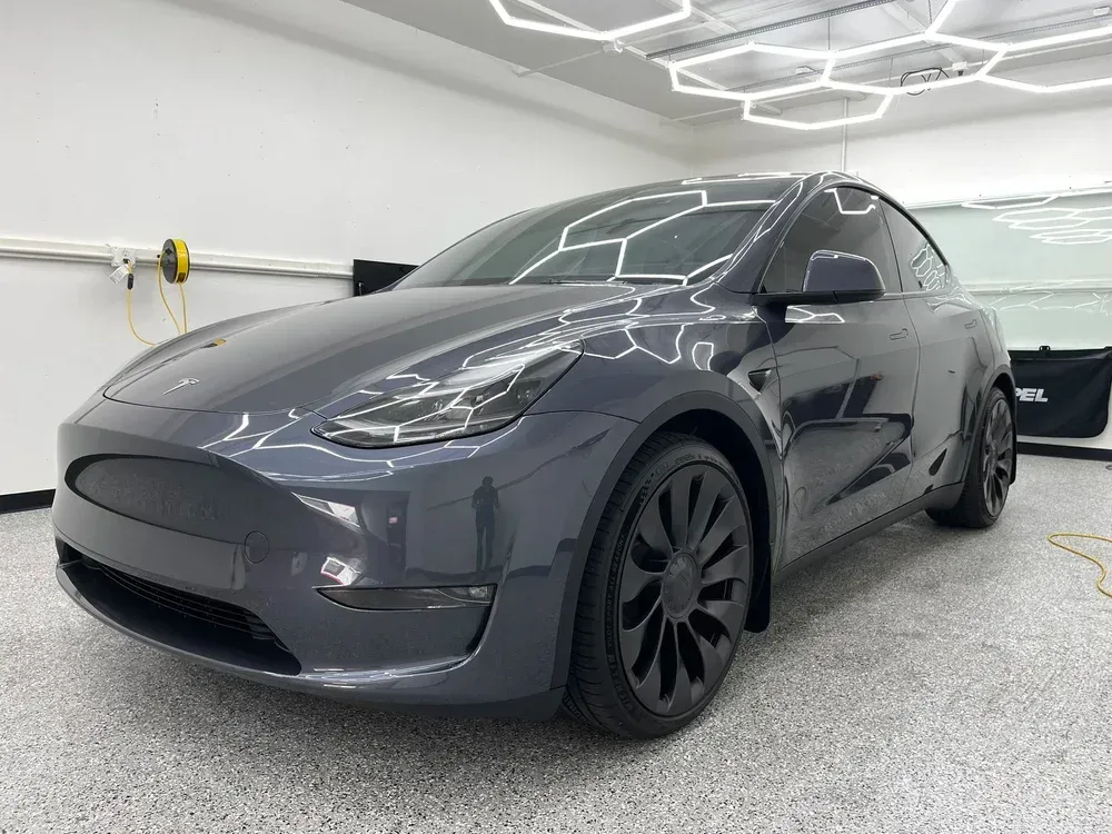 Dark gray Tesla Model Y parked in a garage, front three-quarter view